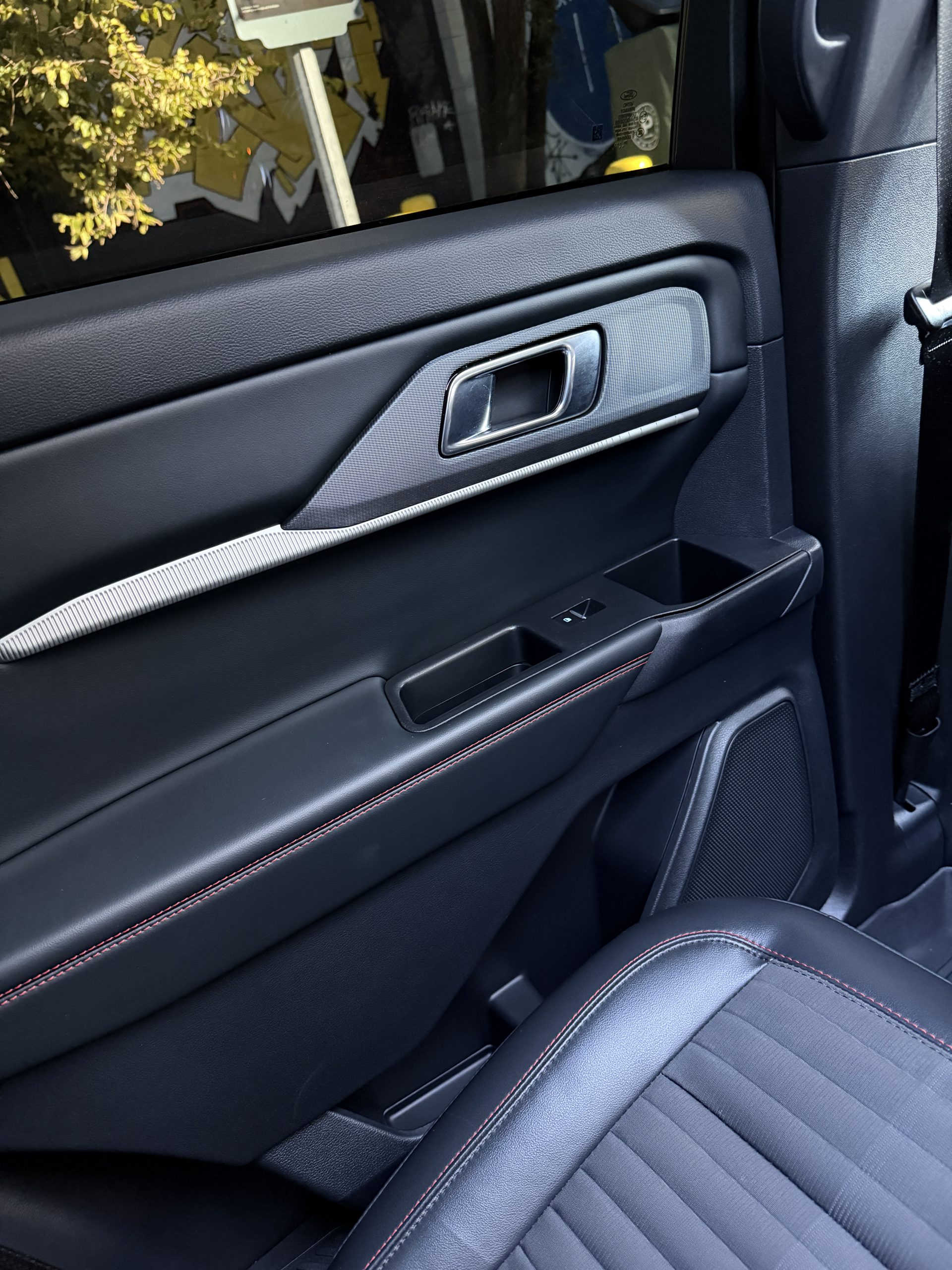 Passenger door handle, window switch and red stitching.